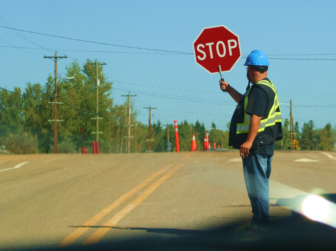 A flagman directs traffic on highway under construction